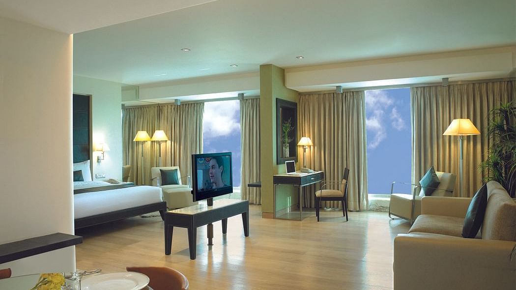 Shot of the expansive suite at our hotel featuring a separate living area, sofa, side lamp, a television, and a king size bed. | Mirage Hotel