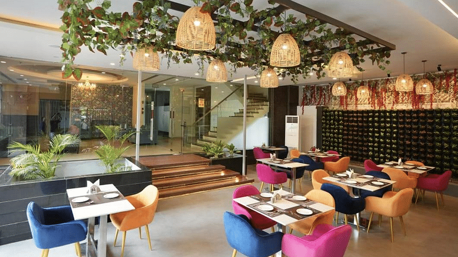 A dining area with hanging decorations, colourful chairs, and set tables, creating a lively atmosphere - VITS Gurugram