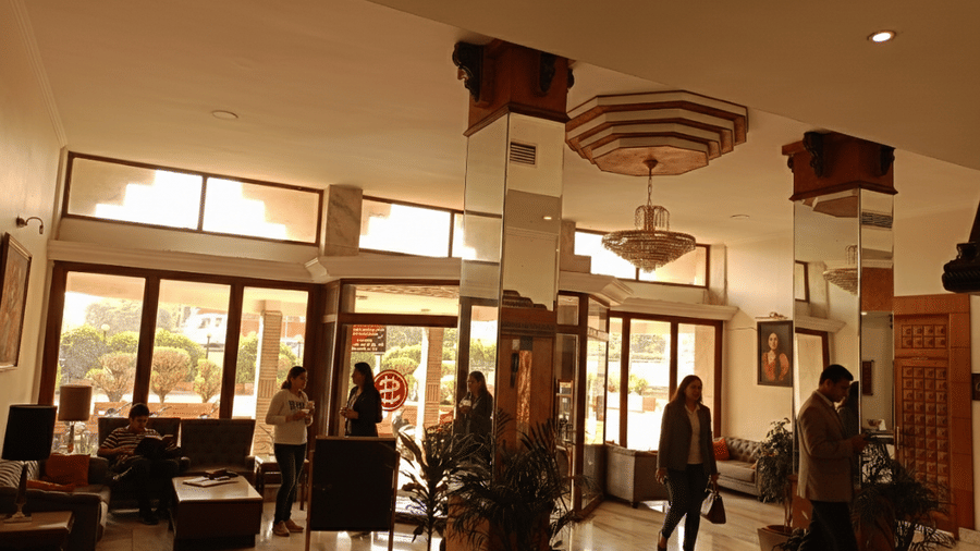 Lobby area at Hotel Gold, Panipat with seating, large windows, and guests walking through the space.