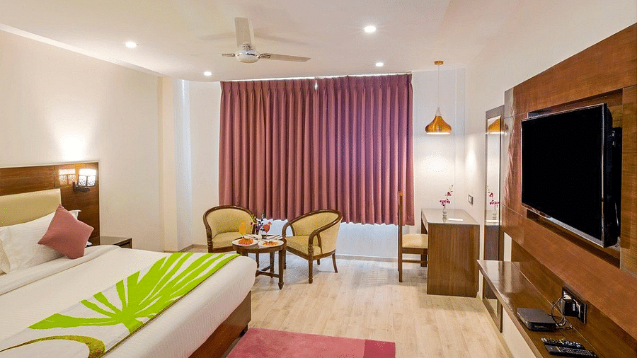 The Premium Room at Regenta Inn DLS with a double bed along with a wall mounted television in front of it.