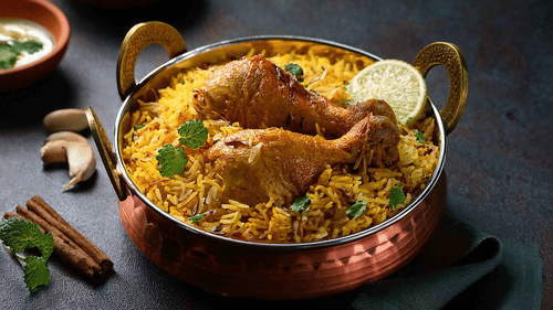 Close-up of biryani served in a copper pot, garnished with herbs and a boiled egg, representing Indian cuisine.