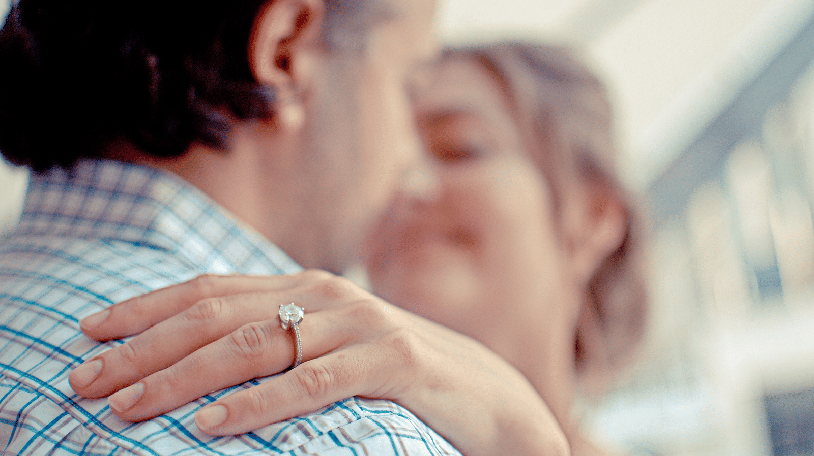 image of a happy couple hugging each other with more focus on the ring on the hand of the woman