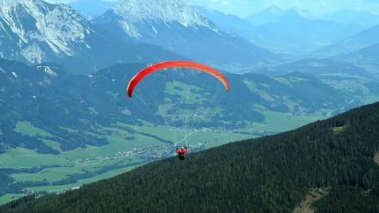A picture of a person paragliding,  mountains in the background