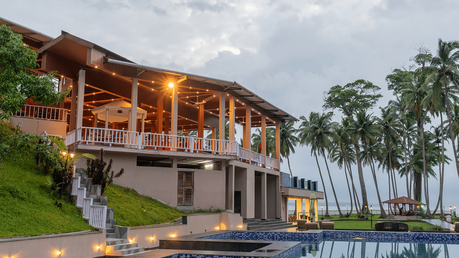 Facade of Silver Sand Sea Princess Beach Resort, Port Blair with a pool and palm trees in front.