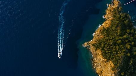 an island and the sea with a speed boat passing by