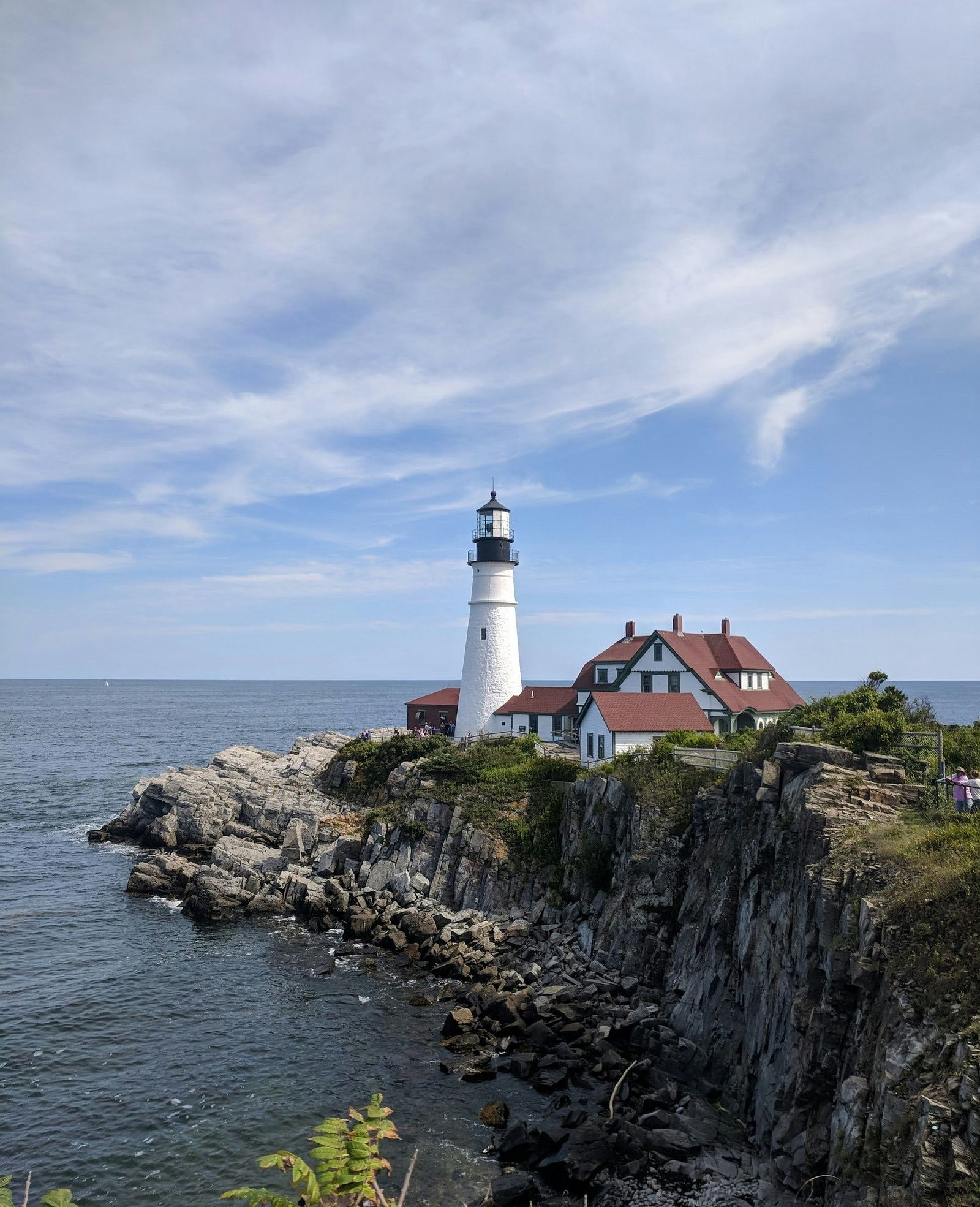 A wide view of a lighthouse on a rocky coastline.
