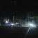 A campsite at night featuring illuminated tents, a glowing campfire, and bright lanterns under a dark sky.