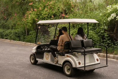 Two people riding in a golf cart on a tree-lined road at Karma Chalets.