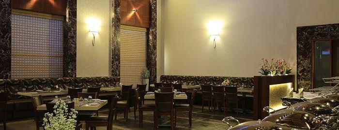 A cosy and intimate seating area with decorative floral arrangements, creating a serene dining atmosphere. - Dhanalakshmi Srinivasan Hotels, Perambalur