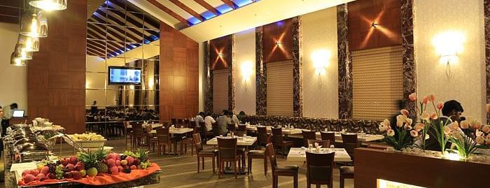 A sophisticated restaurant with an open buffet counter, stylish ceiling design, and ample seating. - Dhanalakshmi Srinivasan Hotels, Perambalur