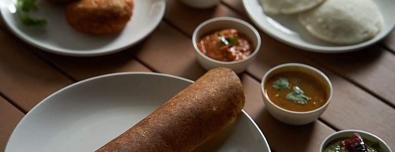 A plate of masala dosa accompanied by different chutney, a plate of idili, and a plate of vada at The Hamuse Hotel, Kodaikanal.