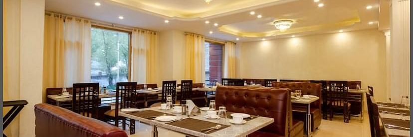 A dining area in La Serene Valley Resort in Manali. The dining room is well-lit and dining tables. | DLS La Serene Manali