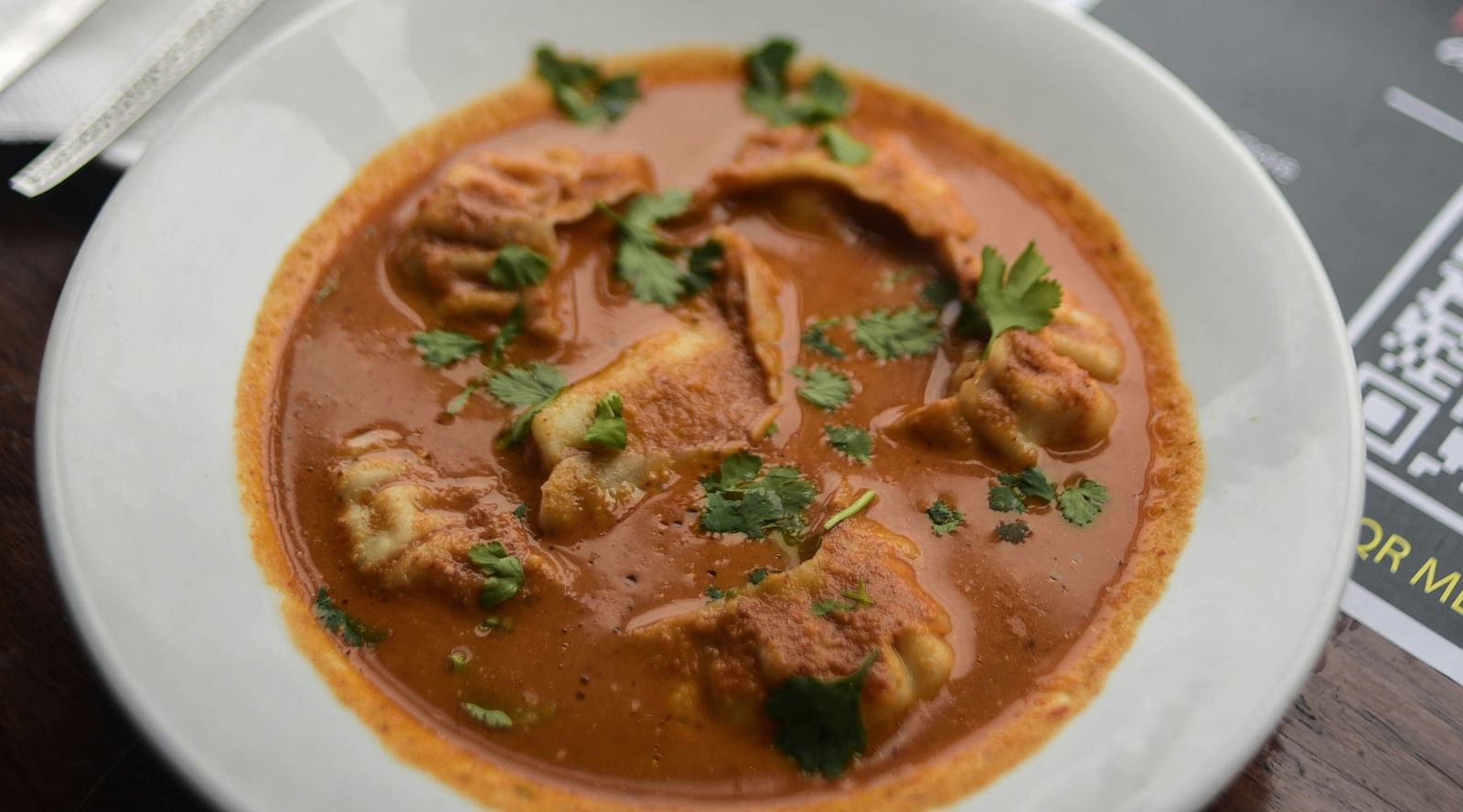 A plate of steamed momos in a curry.