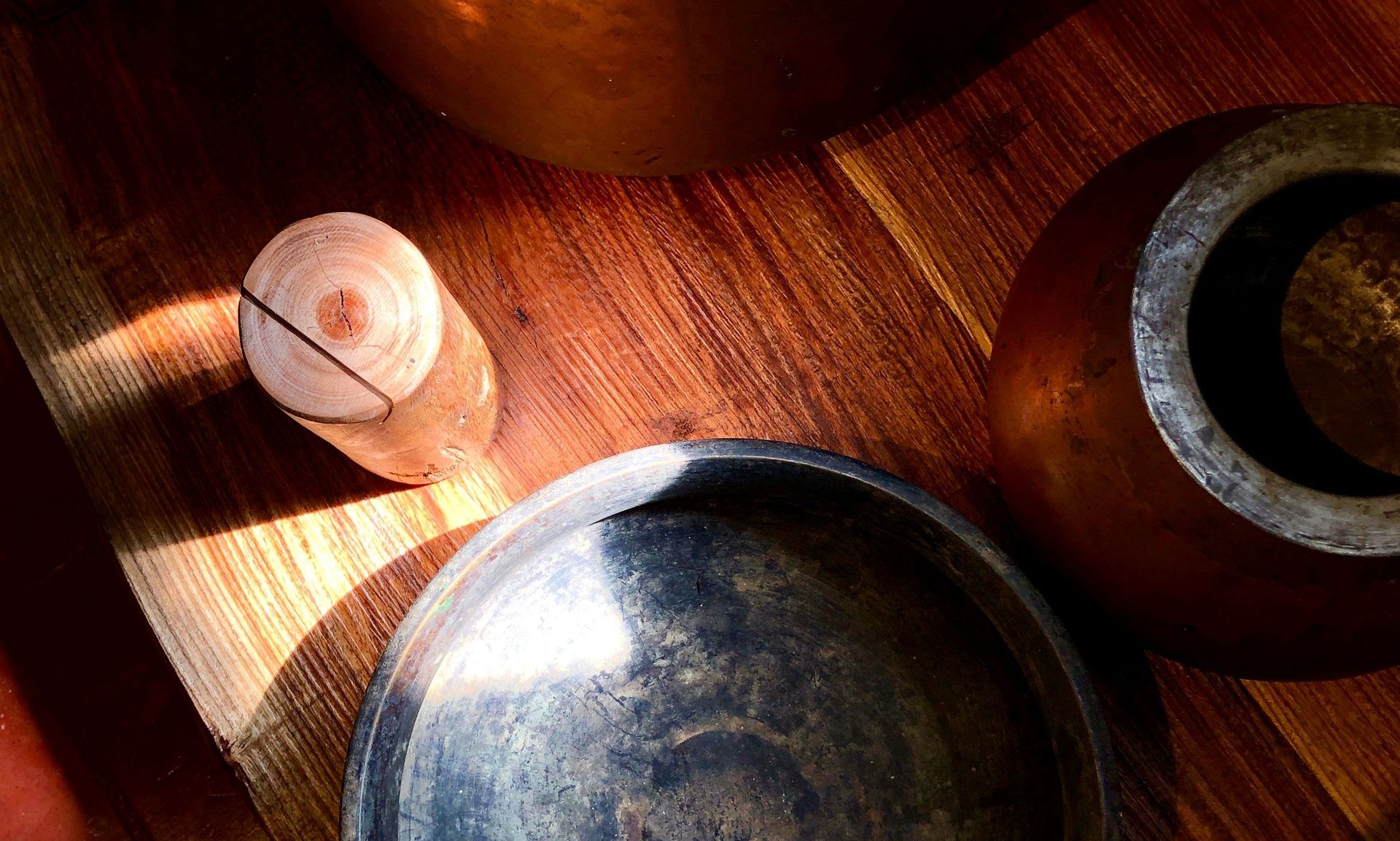 Old copper and brass vessels on a wooden surface.