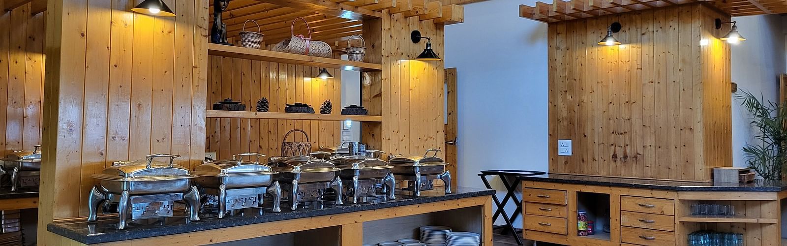 Buffet setup in a wooden-themed dining hall with high ceilings at Dagshai Manor Kasauli - Inde Hotels.