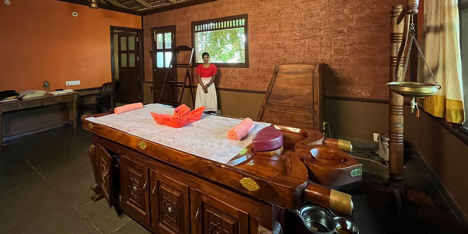 interior of the ayurveda spa with a wooden bed with soft towels in the middle with enchanting aromoas of incess sticks at hoysala village resort in hassan