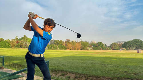 A person playing golf dressed in a blue polo t shirt at karma lakelands.