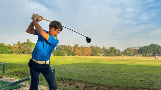 A person playing golf dressed in a blue polo t shirt at karma lakelands.