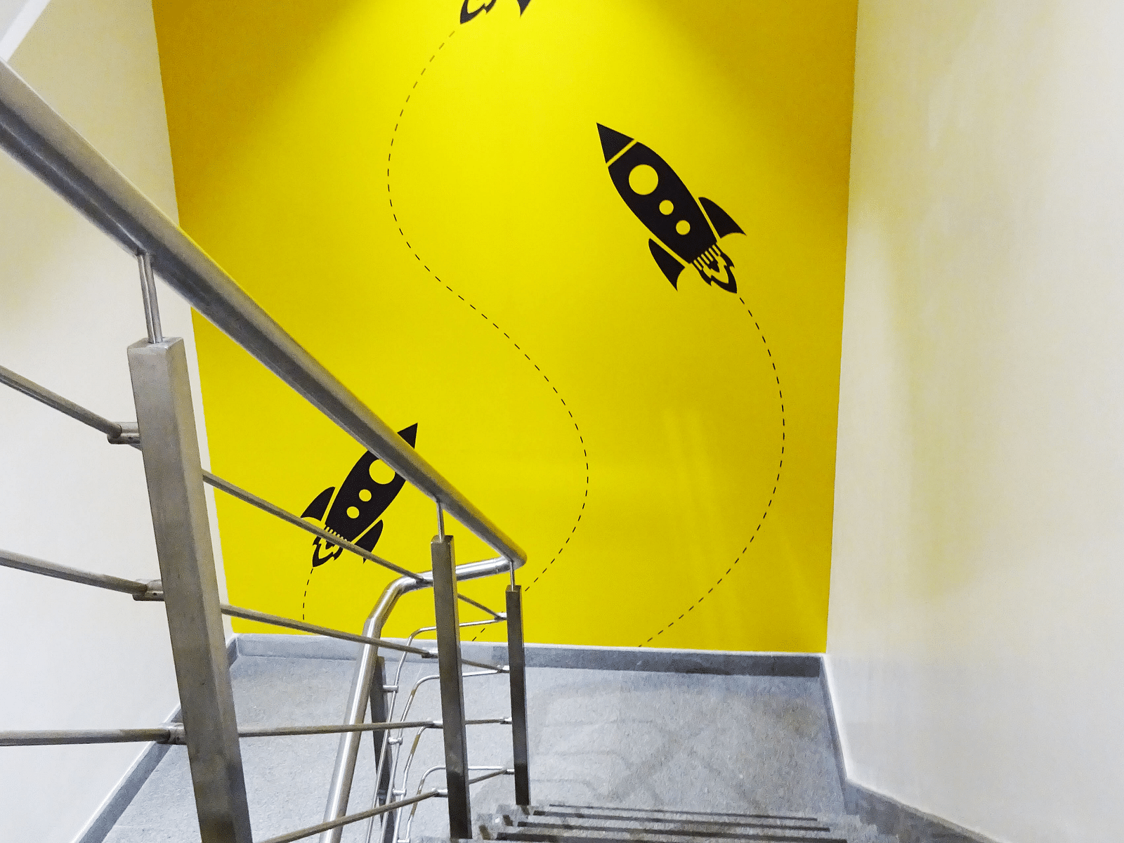 A staircase picture with a yellow wall in the background painted with three rockets.