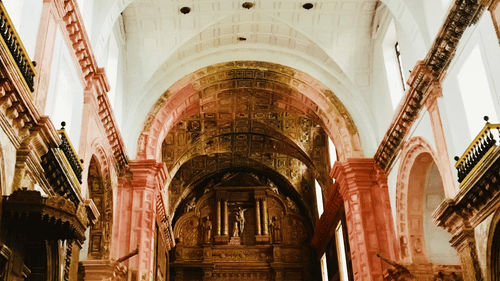 The ornate interior of a church showcasing elaborate architectural details, with arched ceilings and religious artwork.
