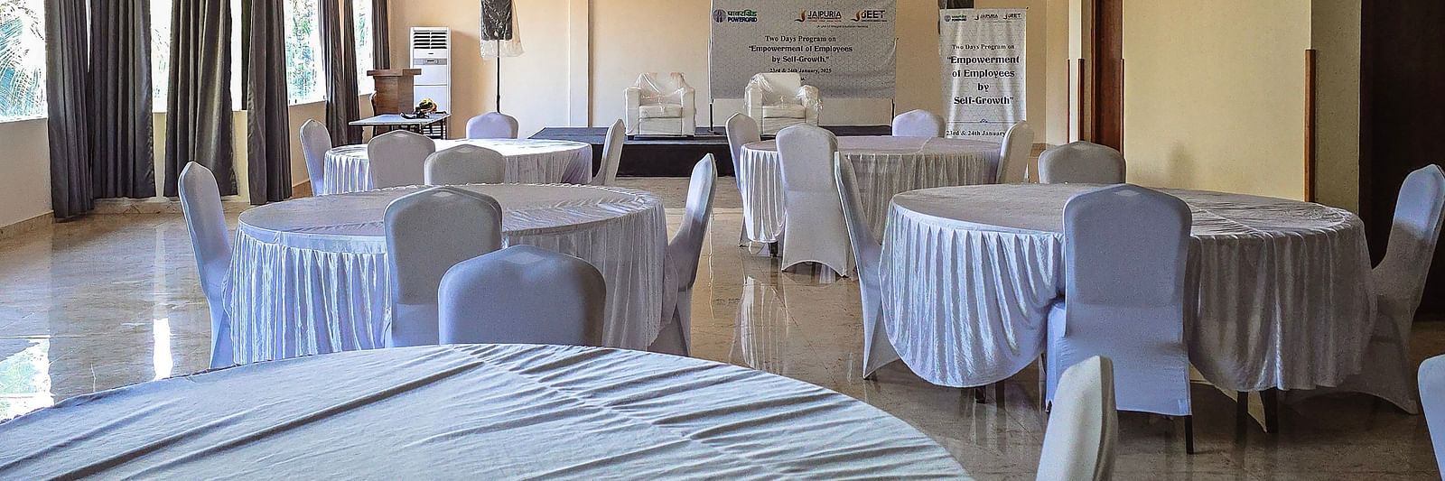 Event space set up with white-covered round tables and natural lighting at The Verda de Miranda Resort.