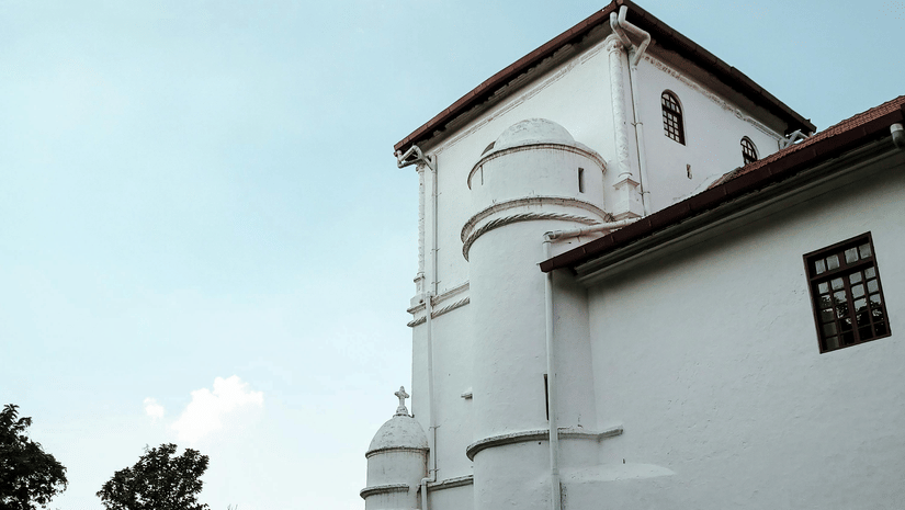 A white building with multiple levels and a tower, photographed from the ground with a clear sky.