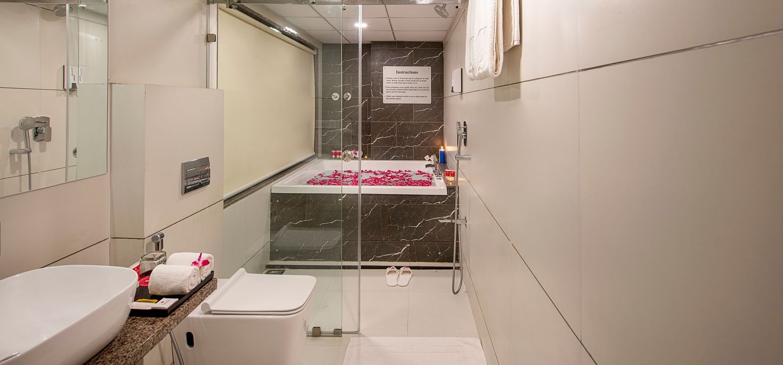 A well-lit hotel bathroom features a modern sink, toilet, and a bathtub - SK Lords Inn Ahmedabad