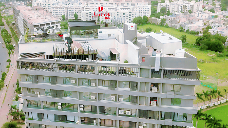 a aerial view of Lords Inn Rajkot showcasing the neighbouring area with lush greenery and other buildings surrounding it
