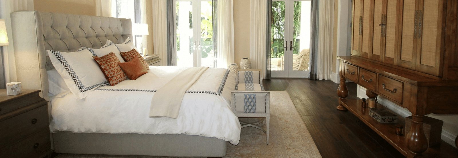 Side view image of the bed with a chandelier hanging over the double bed.
