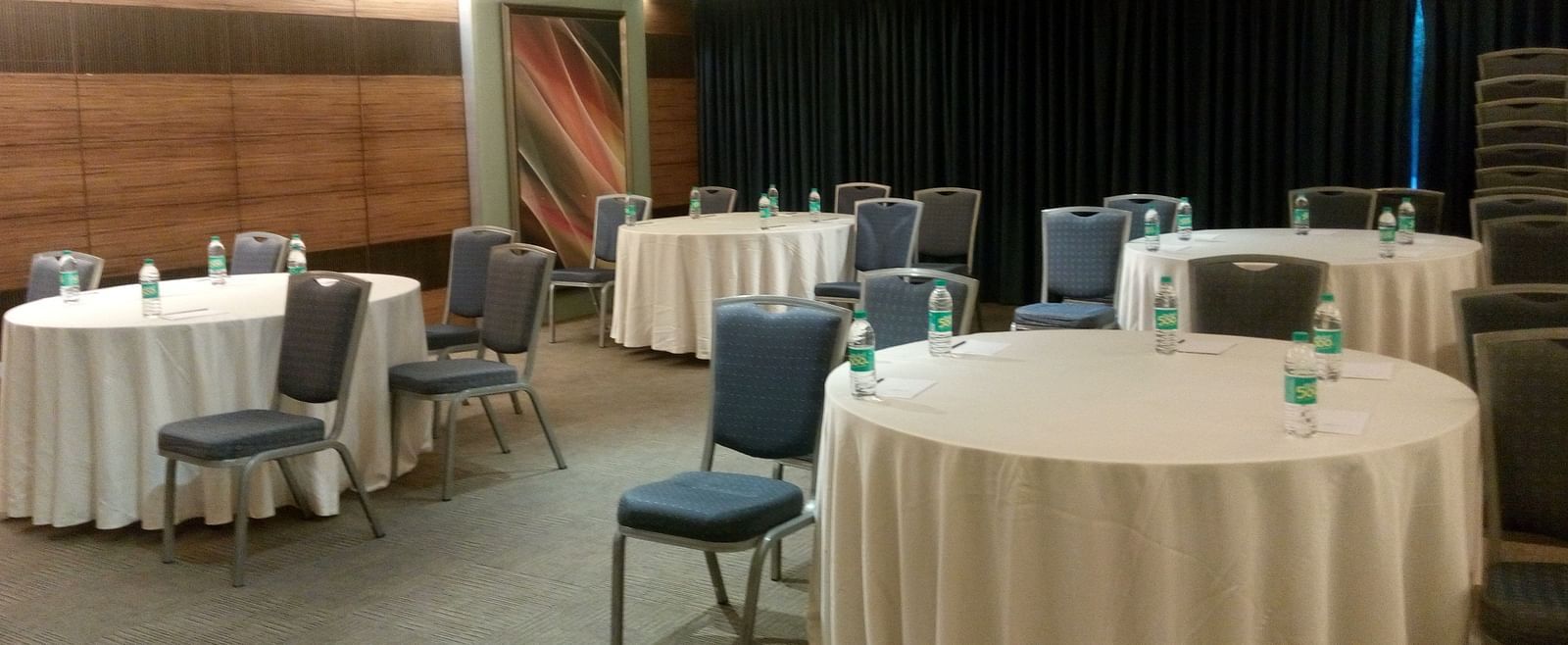 Shot of a meeting hall featuring round tables and black chairs | Mirage Hotel