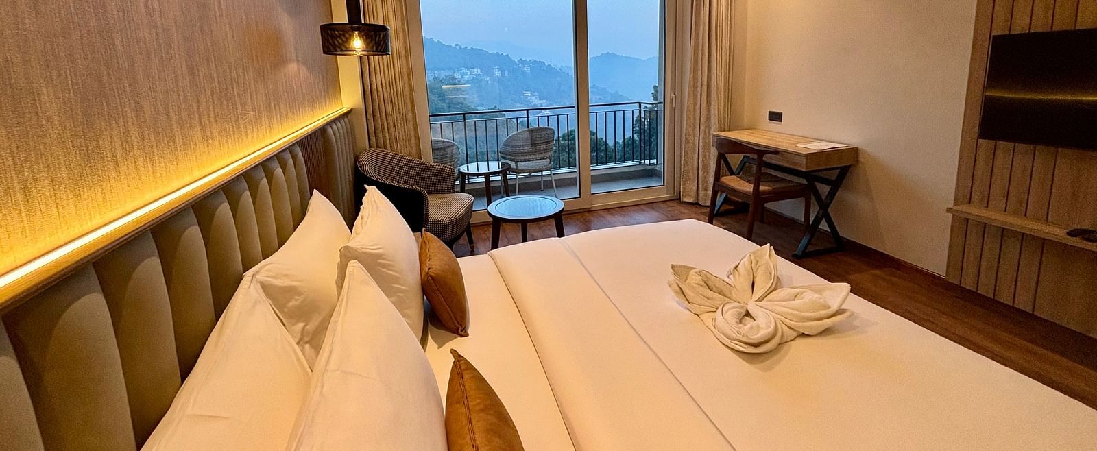 Elegant bedroom with a double bed, ambient lighting, and a large window showing a mountain view –ARNISA Boutique Hotel