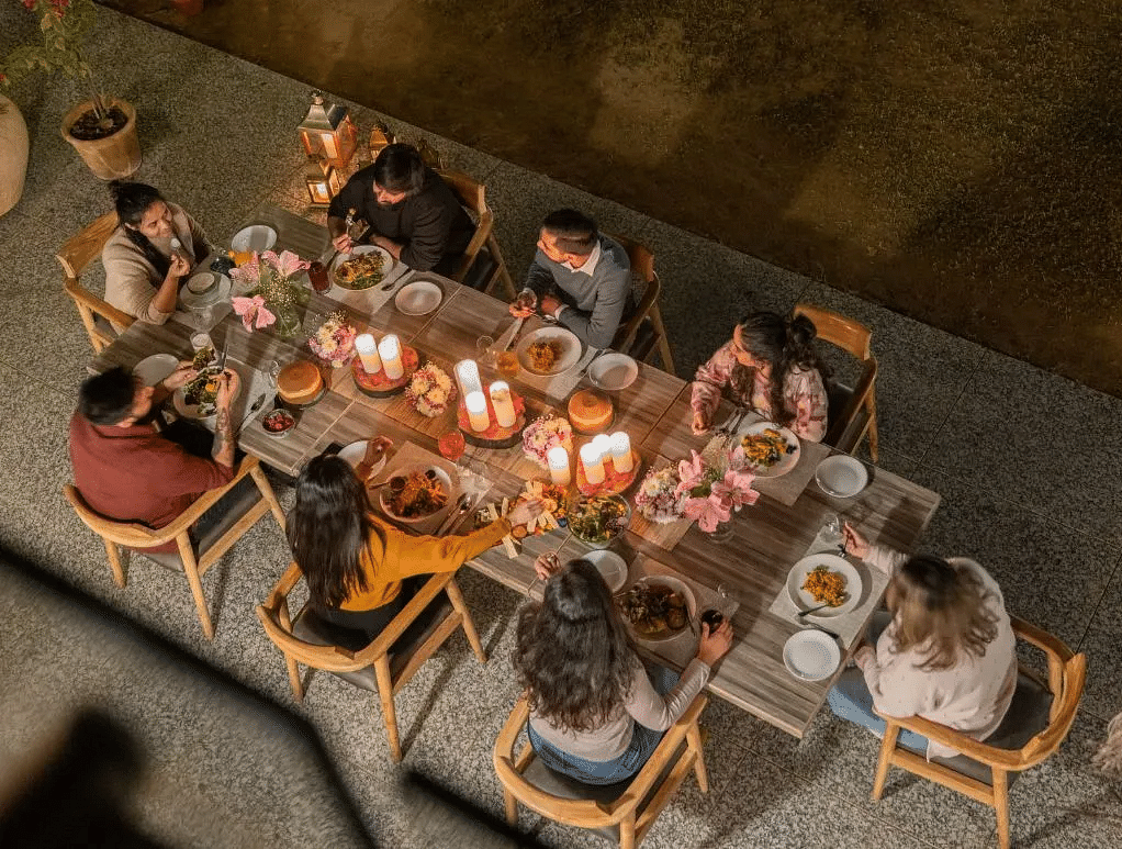 Aerial view of people dining together around a candle-lit dinner table with food and drinks at Karma Chalets.