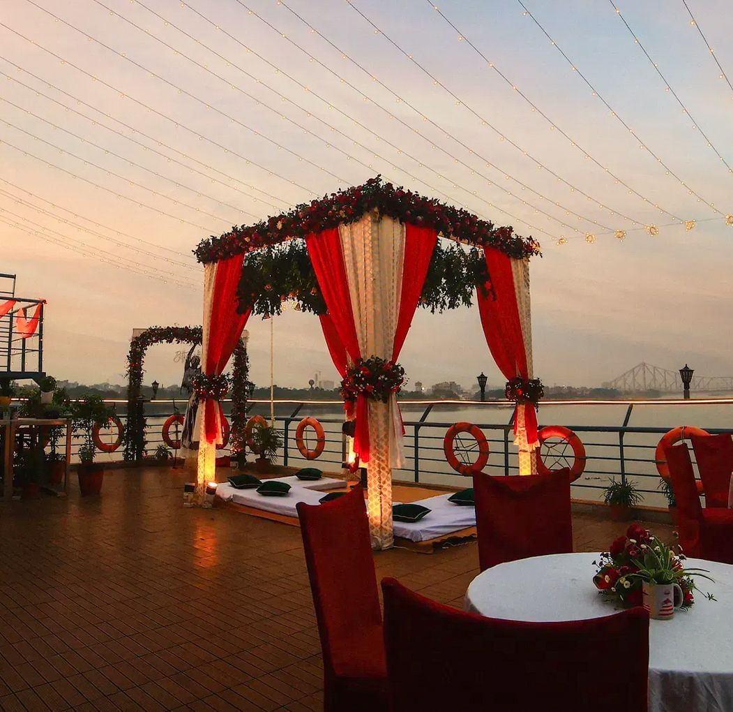 Outdoor dining setup with red and white chairs and draped canopy on a boat.