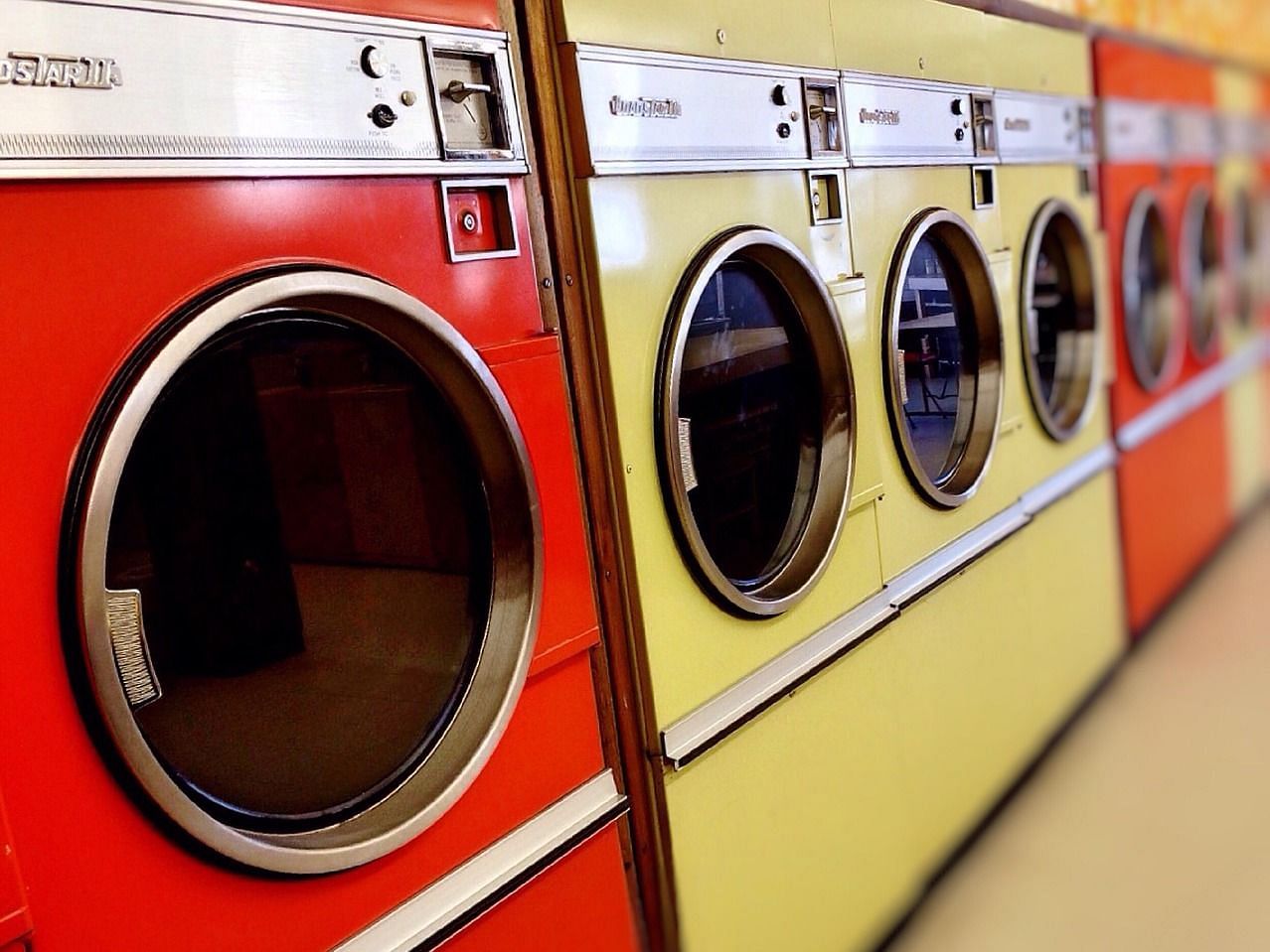 An image showing red and yellow washing machines arranged in a line.