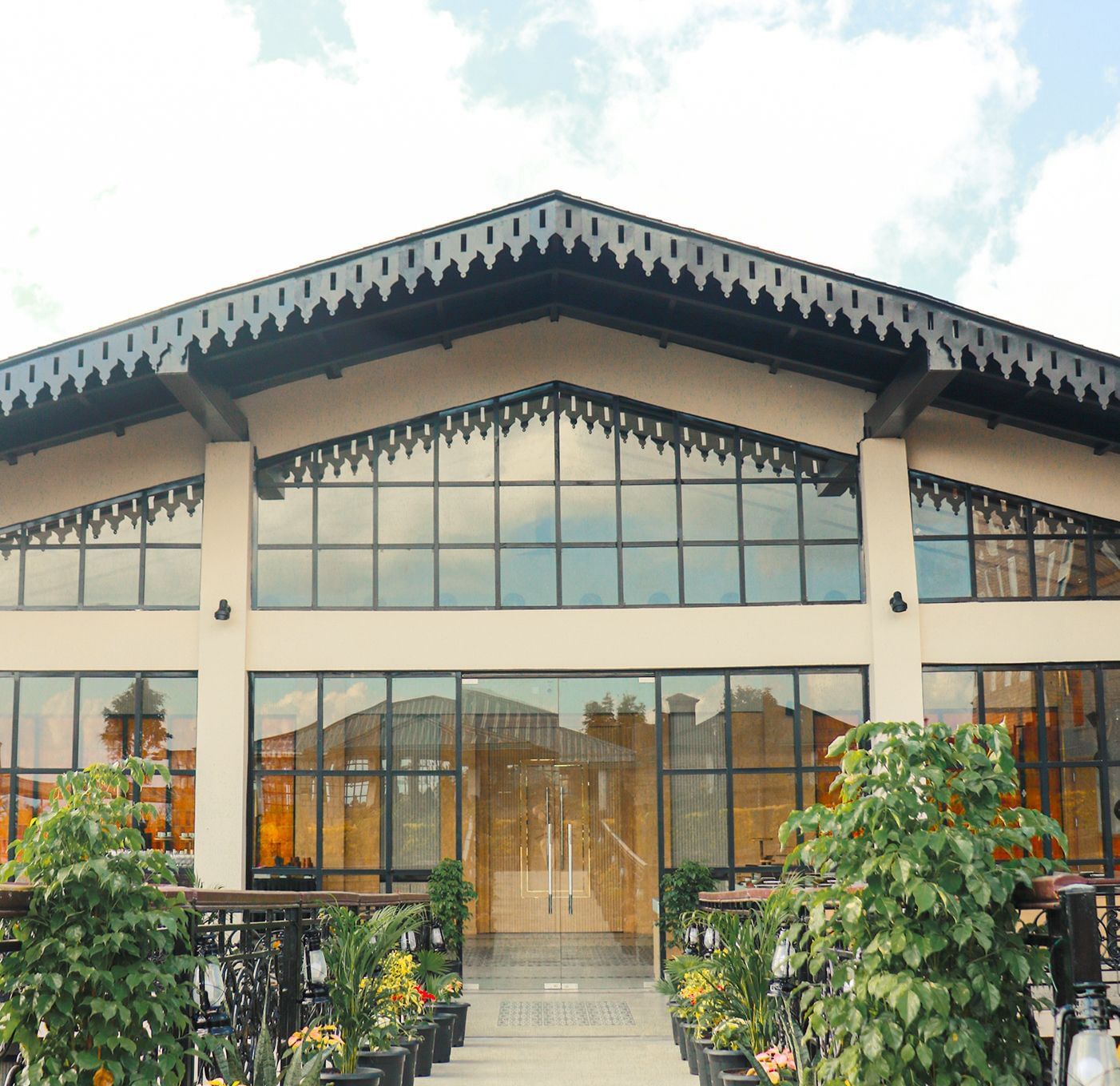 The front exterior of Polo Resort Cherrapunjee during the daytime, showcasing its glass elevation.