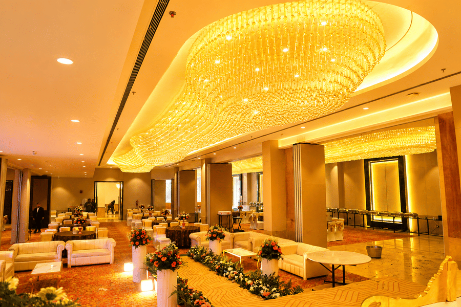 The grand banquet hall interior with a ceiling chandelier and dining arrangement at Ambrosia Sarovar Portico, Haridwar.