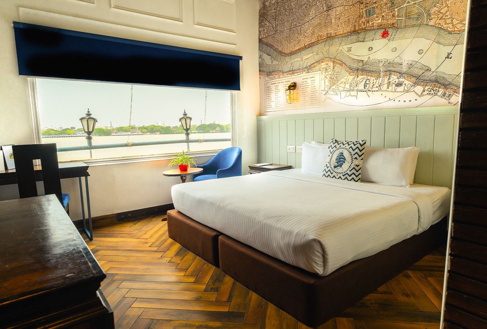 Double bed room at Polo Floatel Kolkata with blue blinds, river view window, and a detailed mural above the bed.