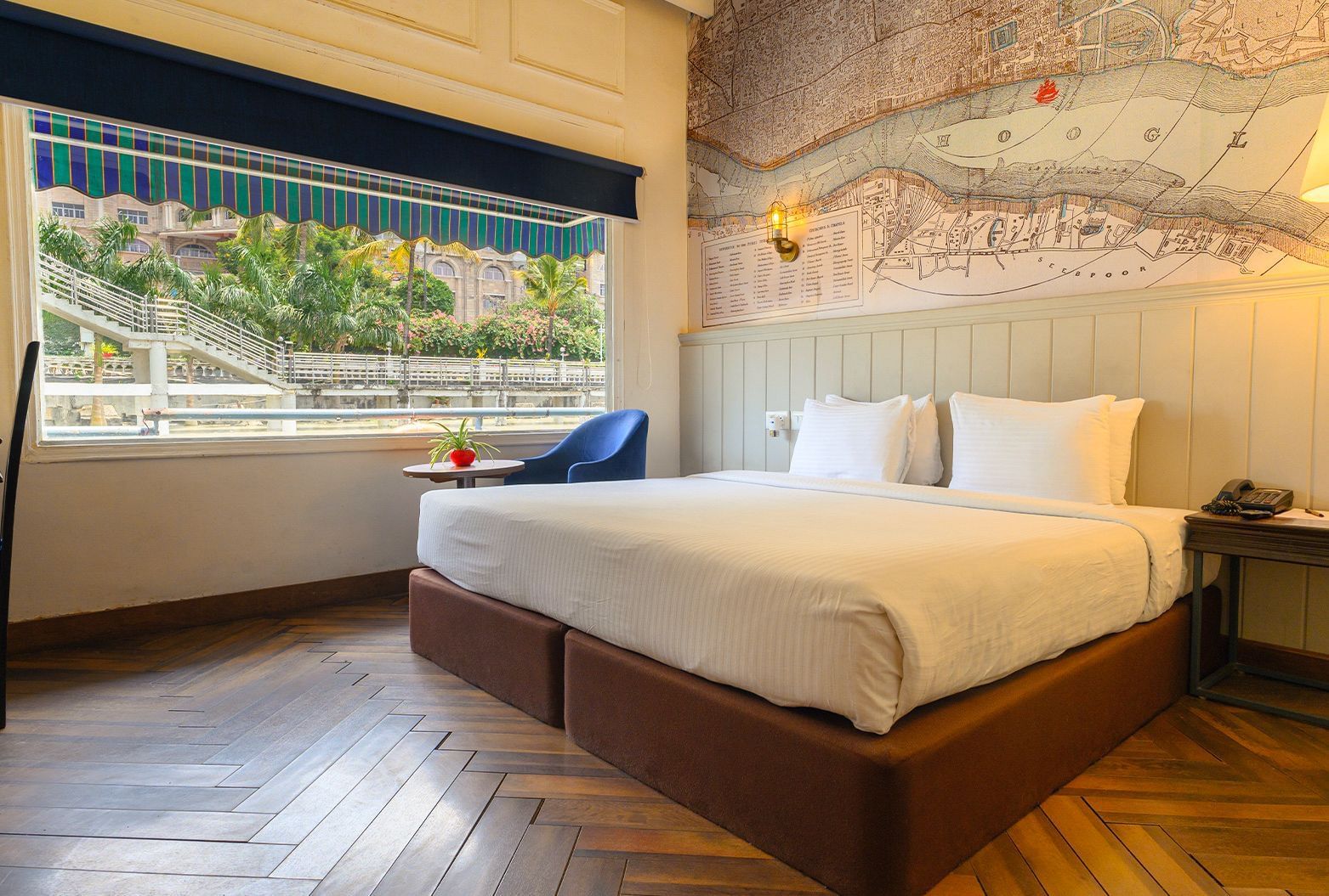 Spacious room at Polo Floatel Kolkata featuring a double bed, wooden flooring, and large window with river view.