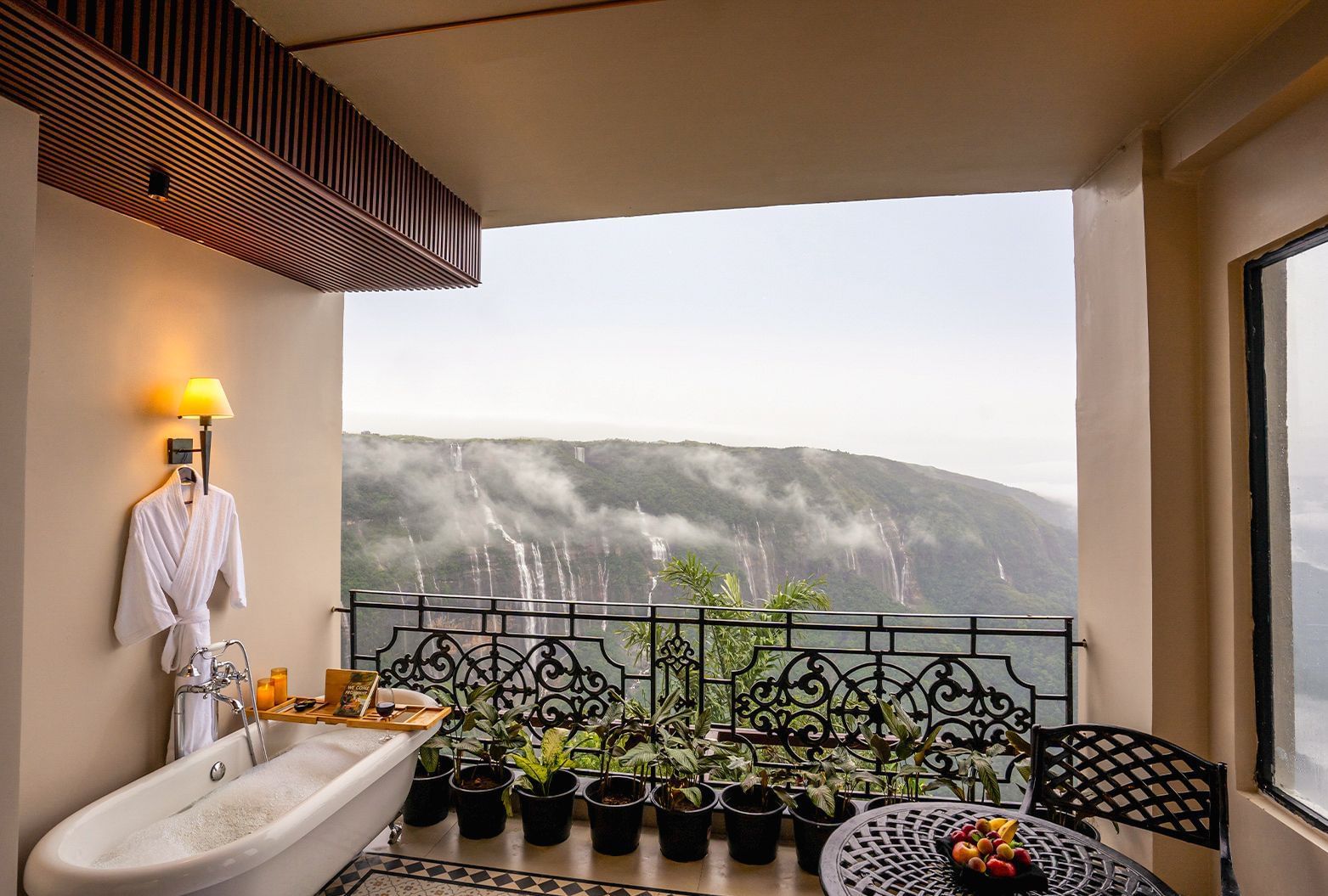 An outdoor bathtub on a balcony at Polo Resort Cherrapunjee, overlooking a misty mountain view.