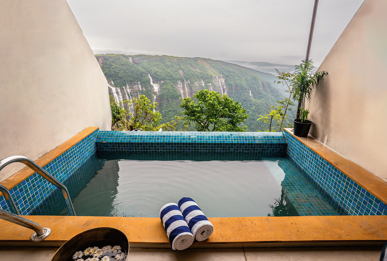 An outdoor hot tub on a balcony at Polo Resort Cherrapunjee, with a scenic mountain view in the distance.