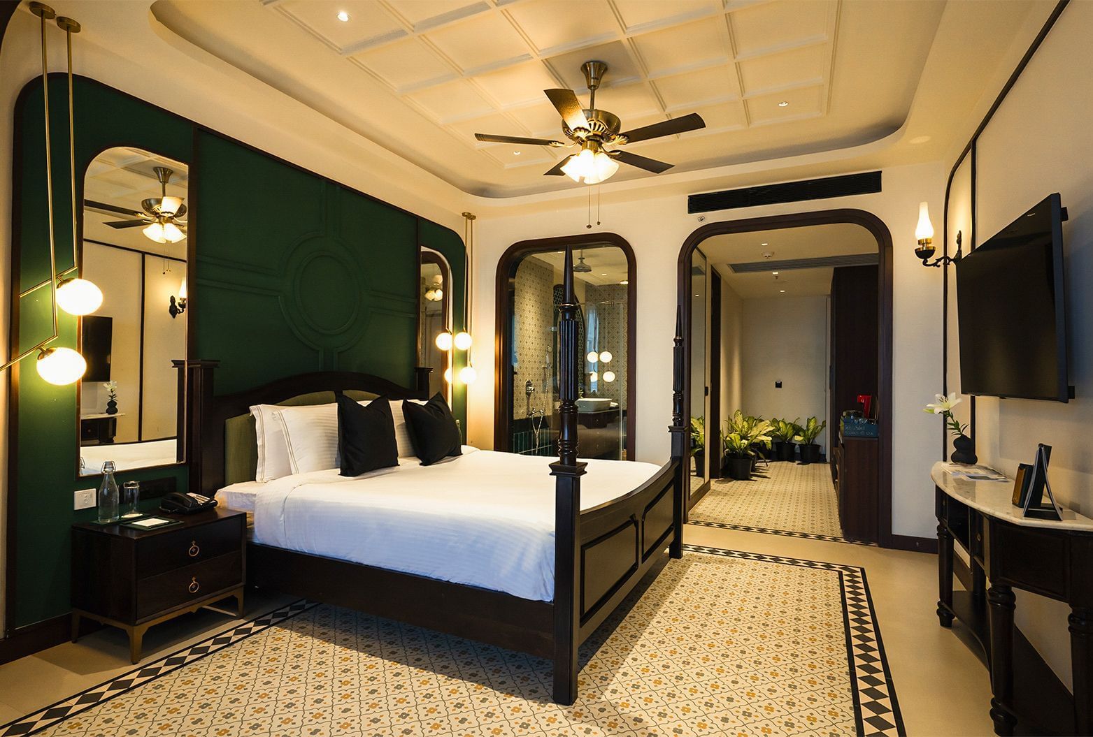 A hotel room at Polo Resort Cherrapunjee with a bed, a green headboard, and decorative mirrors.
