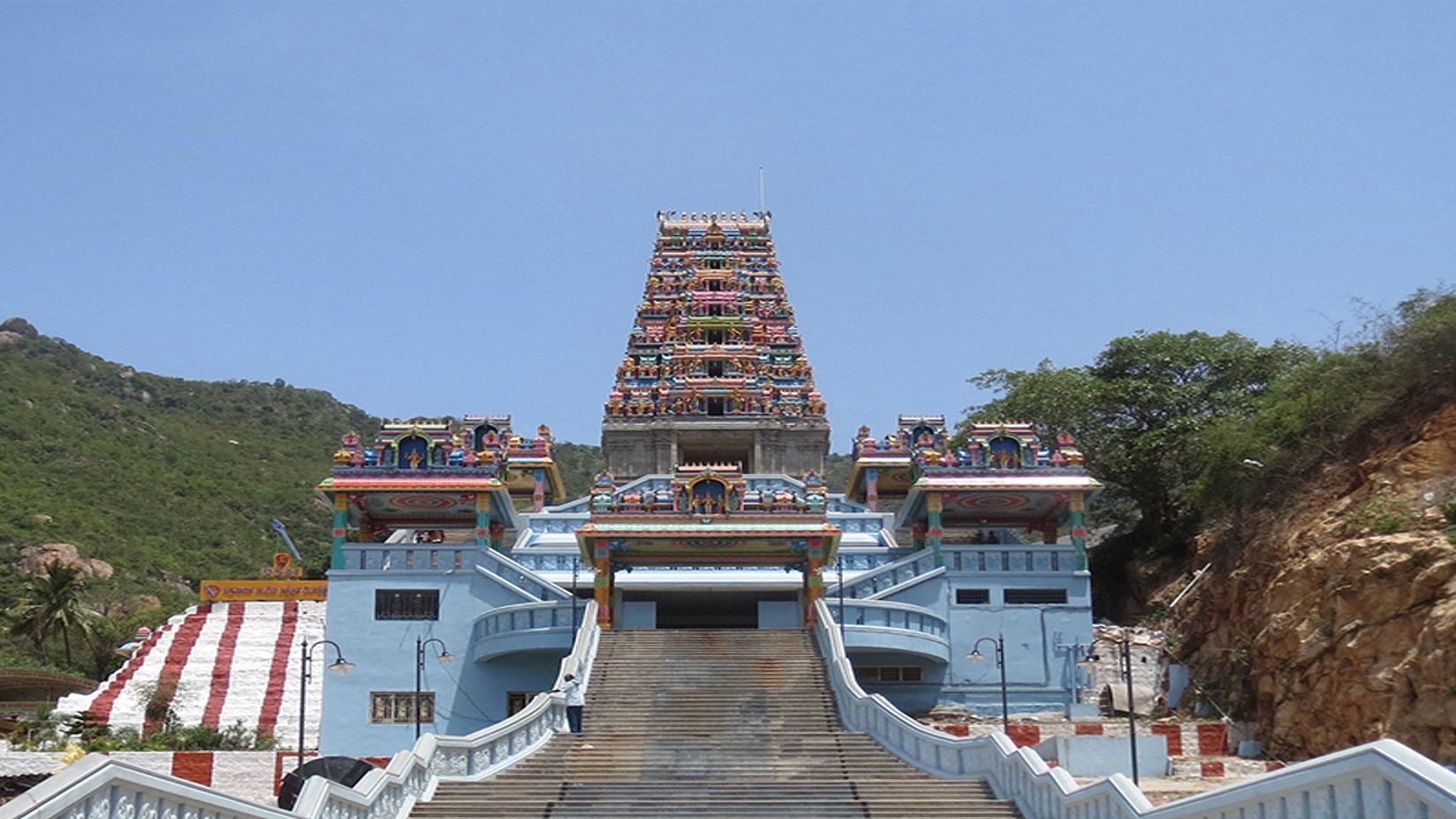 A closer view of a temple with a towering, elaborately decorated structure, accessible by a wide staircase.