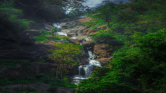 A lush, green landscape with a waterfall cascading down rocks.