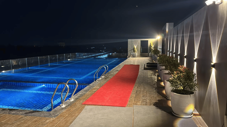 Walkway beside the rooftop swimming pool at Le ROI Digha Hotel, West Bengal, with modern lighting and space to relax.
