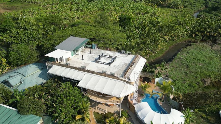 An outdoor patio area with seating, surrounded by dense tropical foliage under a bright sky at Matsya Island Retreat.