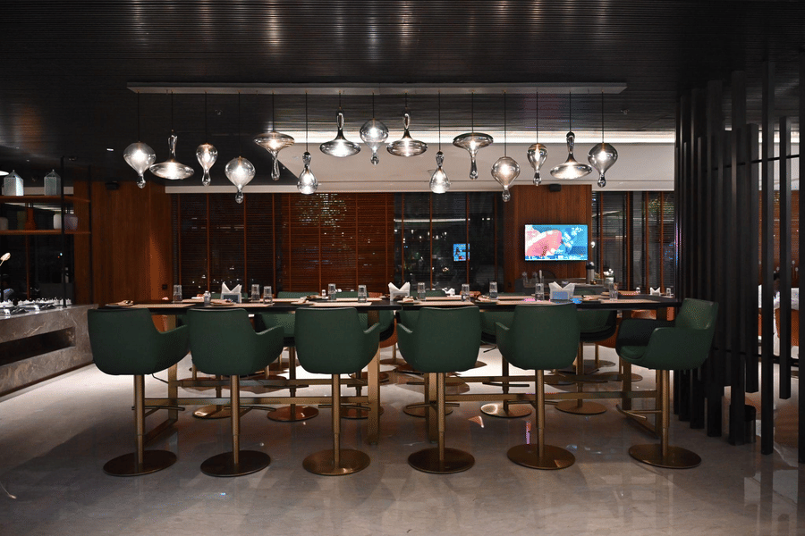A sleek bar lounge featuring green bar stools and ambient lighting, designed for upscale dining and drinks.