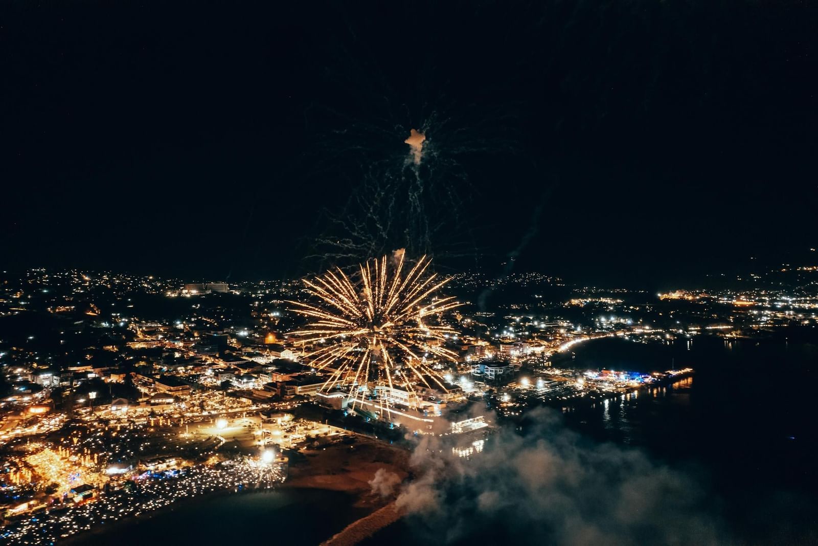 A firework bursts over Montego Bay (Boutique Hotel, Jamaica) at night, illuminating the urban scene with a bright display.