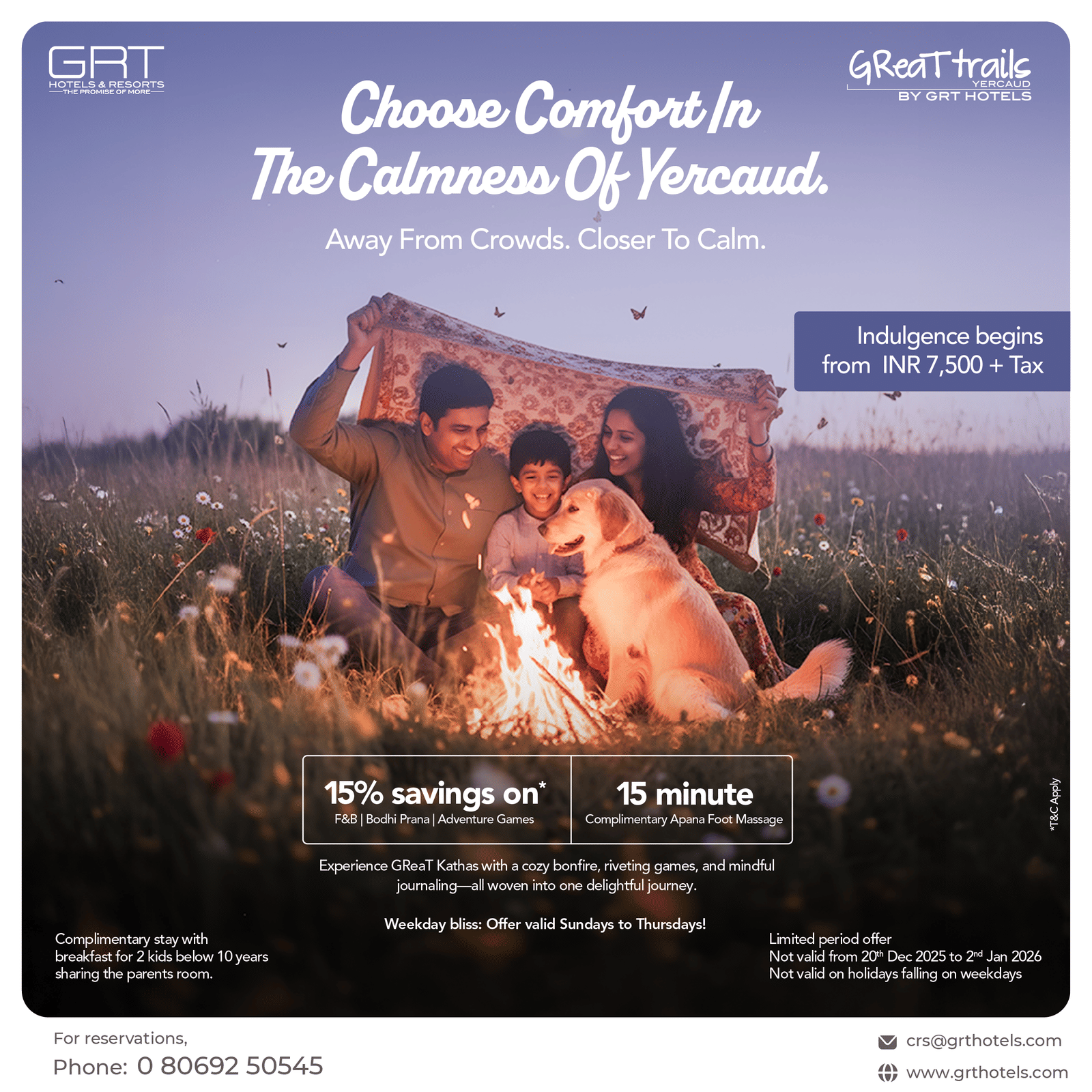 A family sitting beside a glowing bonfire with their dog surrounded by wildflowers enjoying a peaceful evening stay at GReaT Trails Yercaud by GRT Hotels.