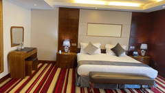 Well lit bedroom with a king bed and striped carpet at The Boma Nairobi.