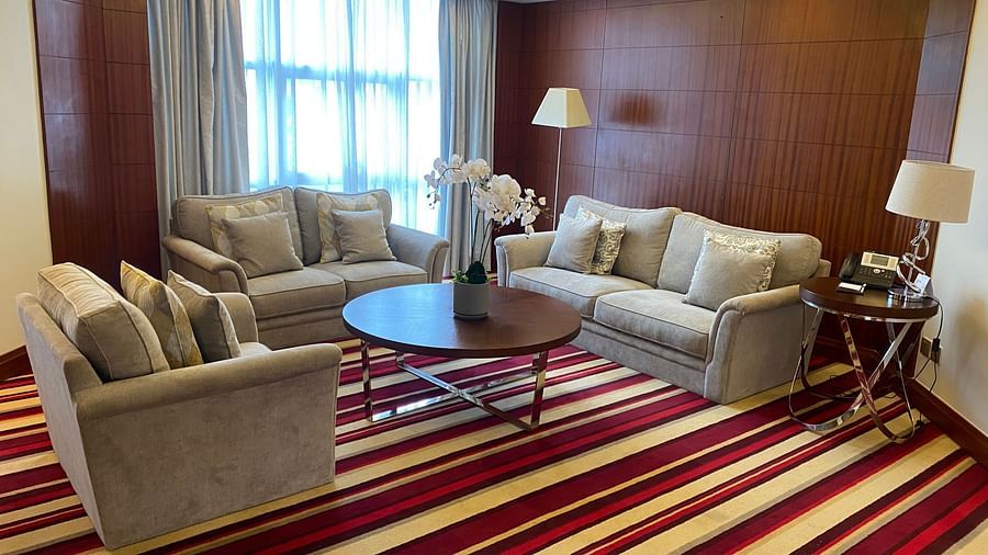 Sitting area with beige sofas surrounding a circular table and striped carpet at The Boma Nairobi.